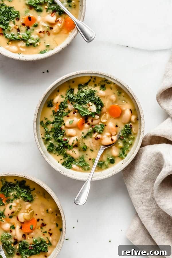 Effortless Elegance: 20 Stunning Date Night Dinners 6 Warm Tuscan white bean soup with kale and carrots, lightly seasoned with red chili pepper flakes, served in tan bowls with a linen on a marble countertop, perfect for an appetizer.