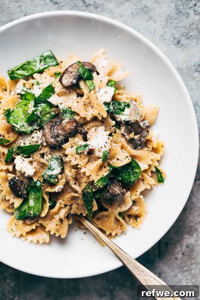 Effortless Elegance: 20 Stunning Date Night Dinners 7 Bowtie pasta generously mixed with sautéed mushrooms, fresh spinach, and a rich, creamy goat cheese sauce, served in a white bowl with a vintage silver spoon.