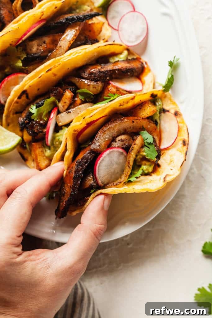 Effortless Elegance: 20 Stunning Date Night Dinners 8 A hand reaching for a vibrant taco filled with roasted vegetables, fresh cilantro, and sliced radishes, part of a line-up on a white serving platter with lime wedges for date night.