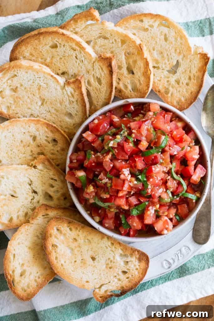 Effortless Elegance: 20 Stunning Date Night Dinners 9 Fresh tomato bruschetta, finely diced and seasoned, served in a white bowl surrounded by perfectly toasted bread slices, set against a green and white linen.