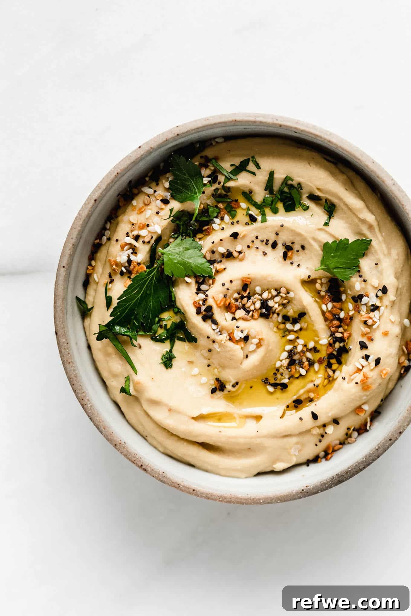 Everything Bagel Seasoned Hummus 2 everything bagel hummus in a bowl, garnished.