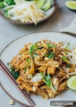 A beautifully plated serving of Vegan Pad See Ew with chopsticks and fresh garnishes.