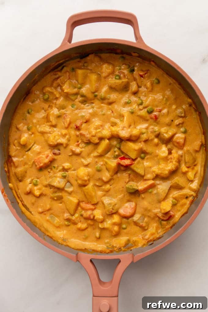 The finished vegetable korma, rich and creamy, presented in a pink pan.