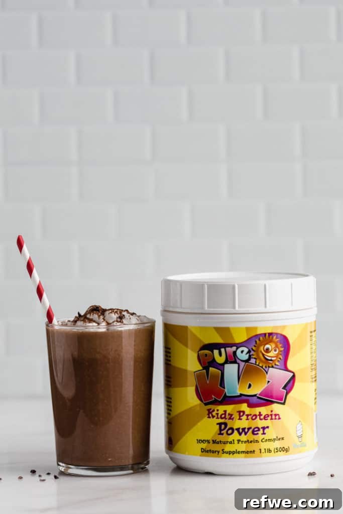 Blended Cocoa Chill 3 A glass of frozen hot chocolate next to a container of plant-based protein powder, highlighting the healthy aspect of the drink.