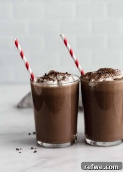 Two glasses of healthy frozen hot chocolate garnished with coconut whipped cream and chocolate shavings.