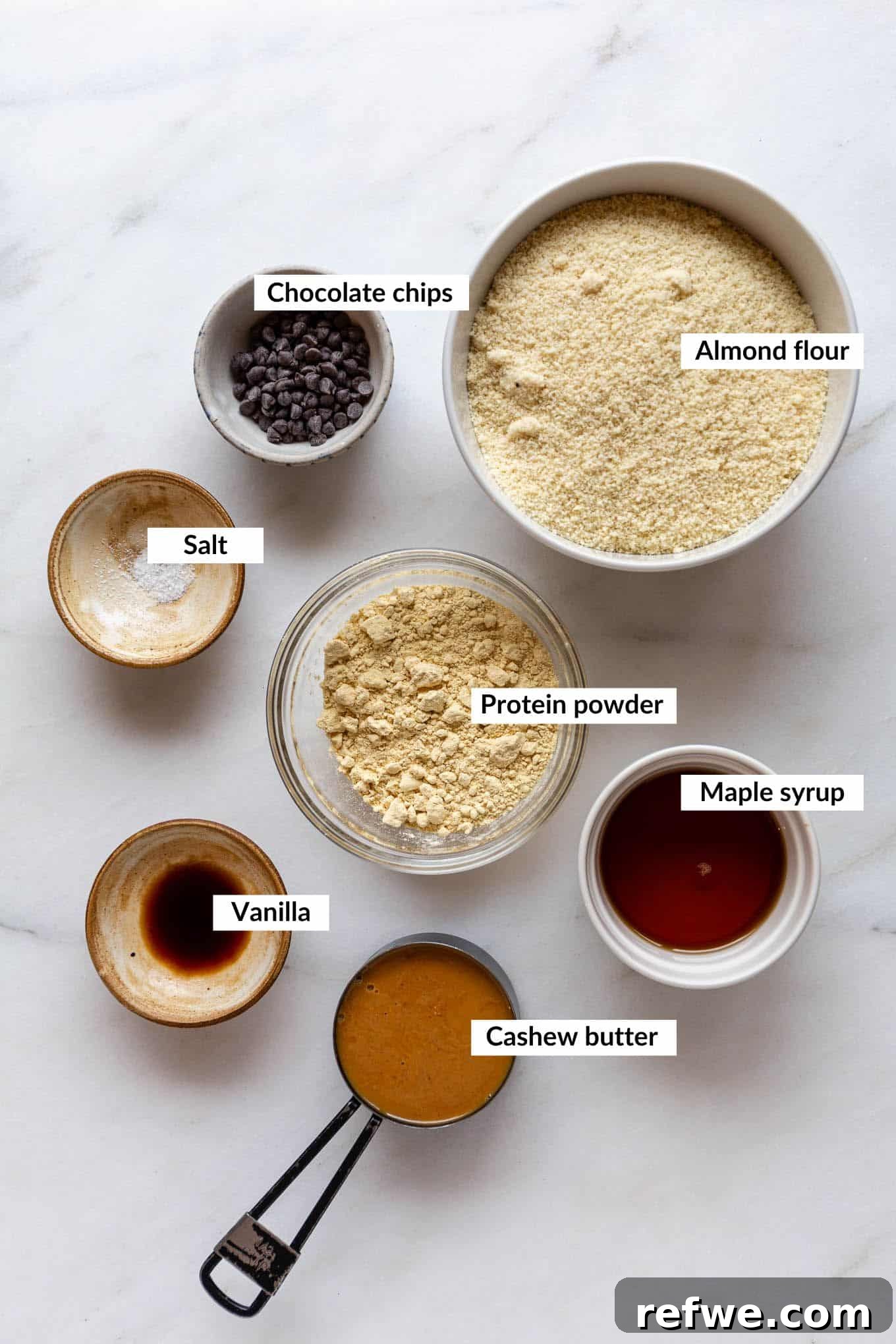 Protein Packed Cookie Dough Bites 3 Collection of key ingredients for cookie dough protein balls, including almond flour, protein powder, cashew butter, and chocolate chips.