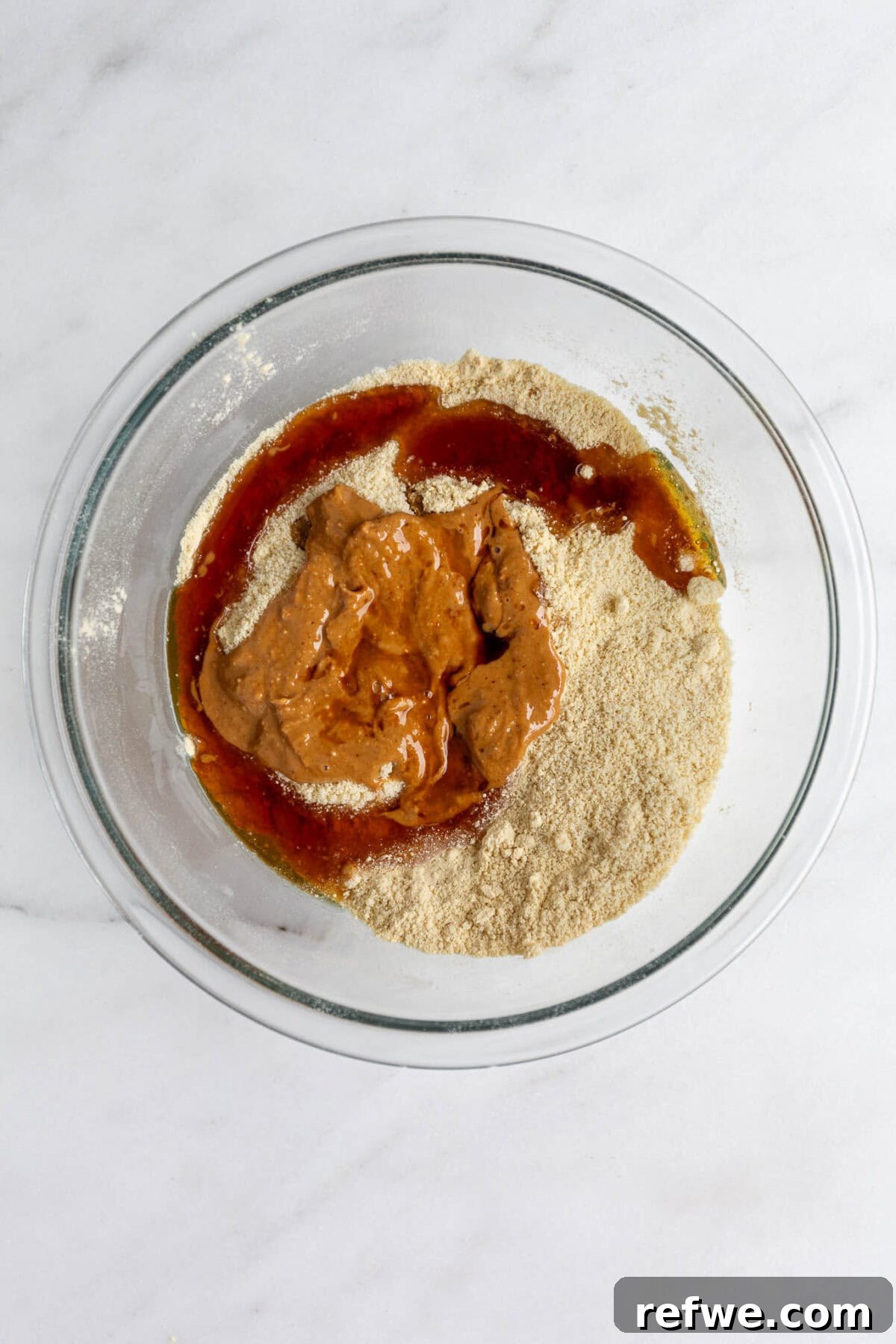 Protein Packed Cookie Dough Bites 5 Cashew butter, maple syrup, and vanilla extract being added to the almond flour mixture.