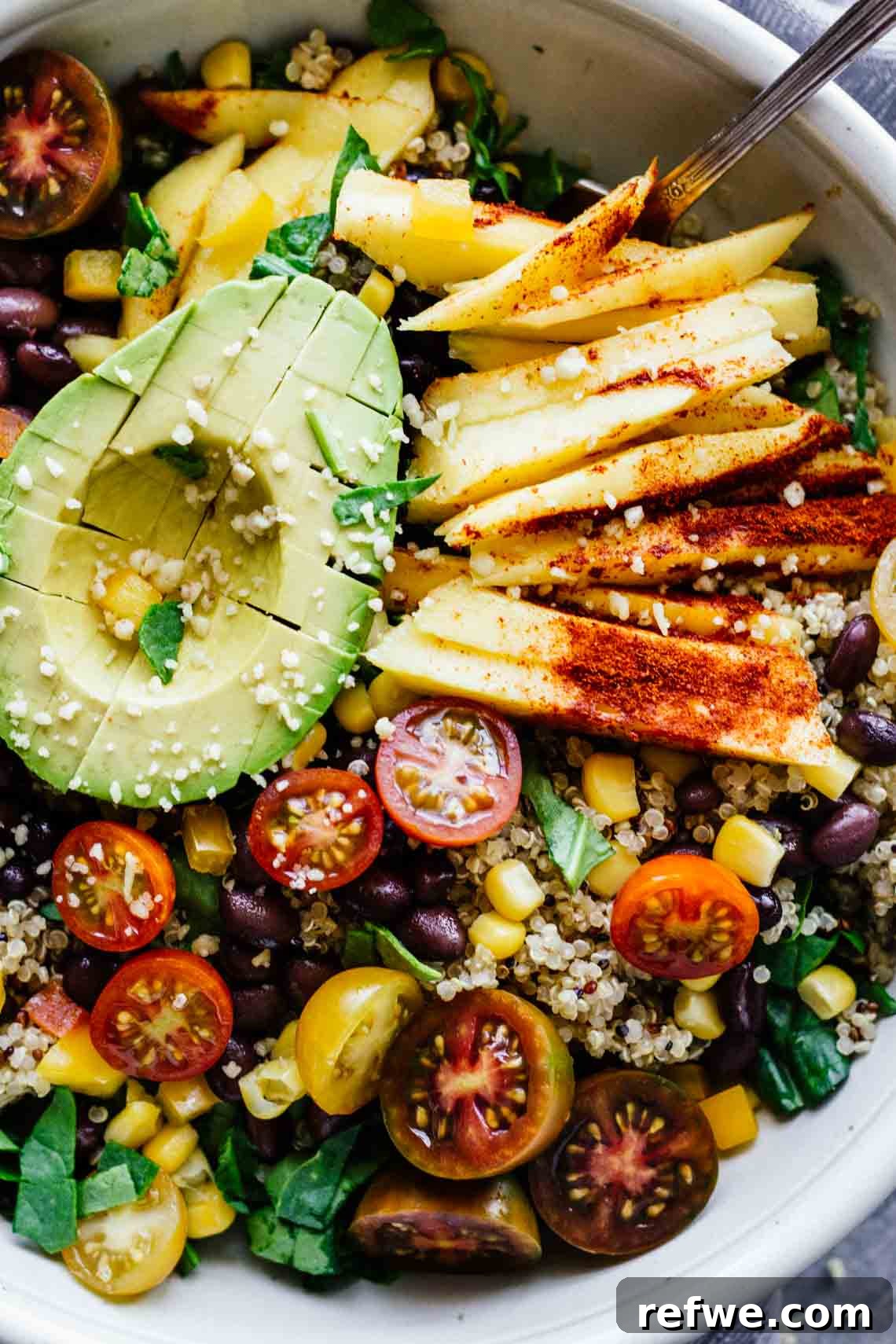 A refreshing chili mango bowl, vibrantly colored and topped with a creamy half-avocado, perfect for a light, flavorful meal.