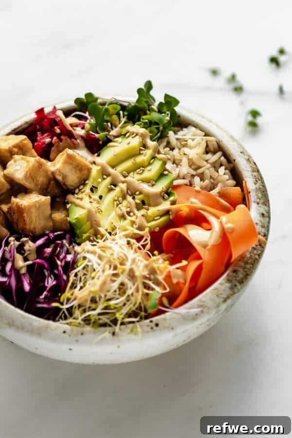 A vibrant bowl featuring crispy tofu, an assortment of fresh vegetables, and fluffy rice, all generously coated in a delectable dragon sauce.
