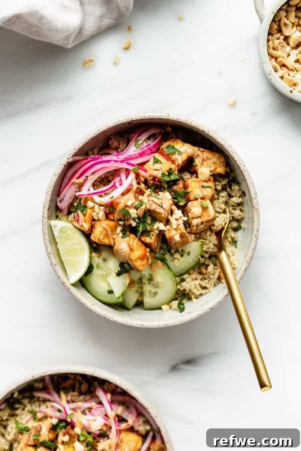 A vibrant satay tofu bowl complete with fluffy quinoa, crisp cucumber slices, and a rich, spicy peanut sauce.