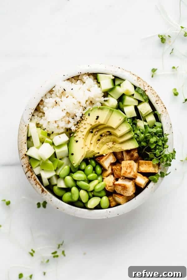 A beautifully arranged vegan poke bowl with rice, firm tofu, edamame, and vibrant greens.