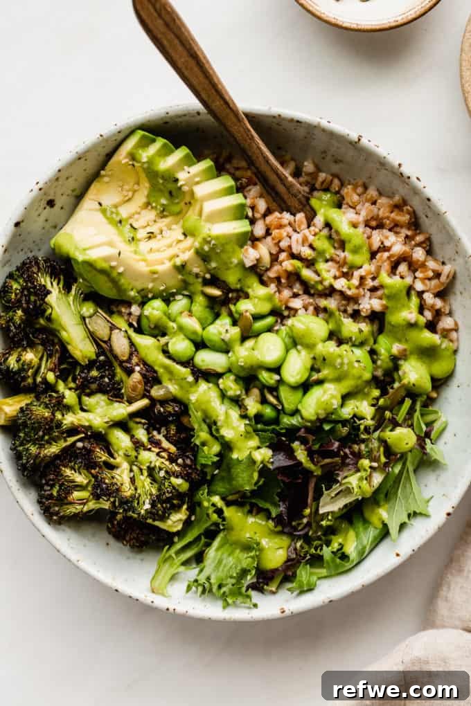 A verdant Green Goddess bowl generously topped with creamy green goddess dressing, farro, and various green vegetables.