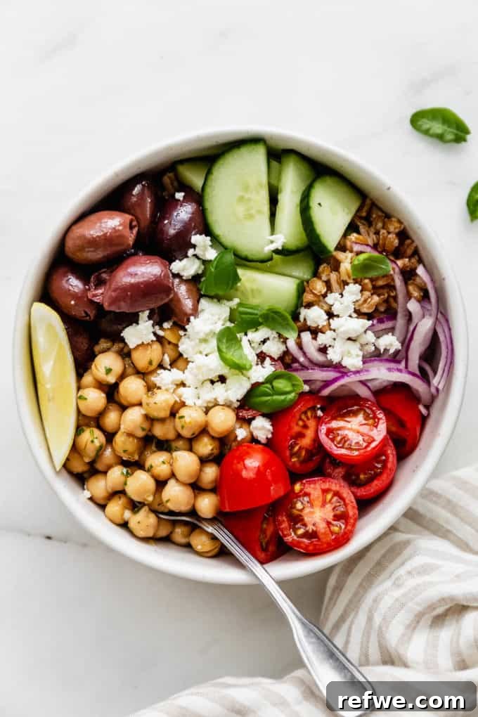 An appetizing Greek power bowl featuring chickpeas, cherry tomatoes, Kalamata olives, and fresh cucumber slices.