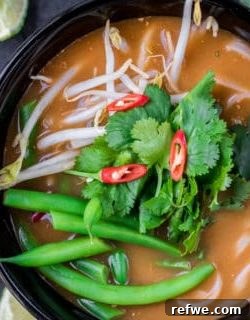 A vibrant bowl of homemade Tom Yum soup with noodles and fresh garnishes, ready to serve.