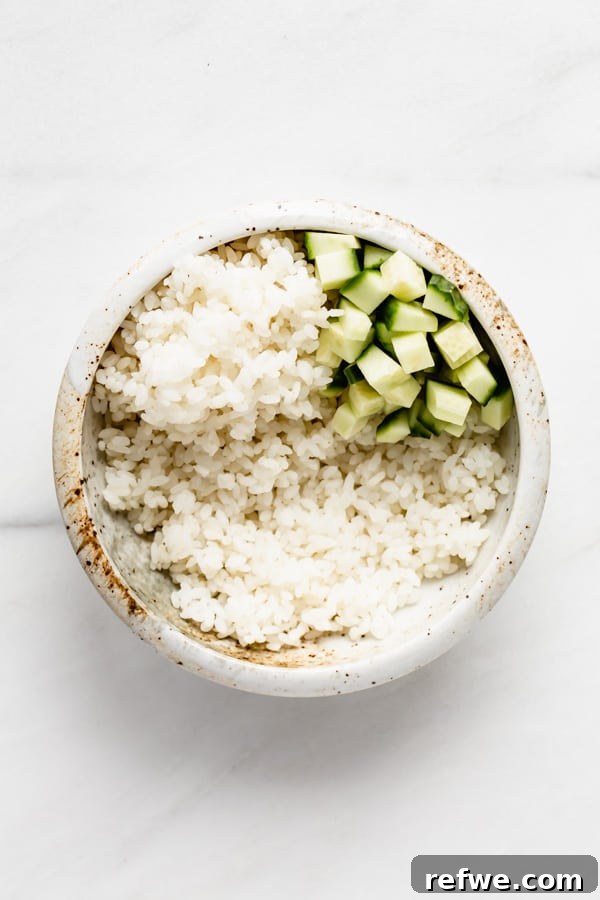 A bowl of rice with neatly arranged cucumber slices on top.