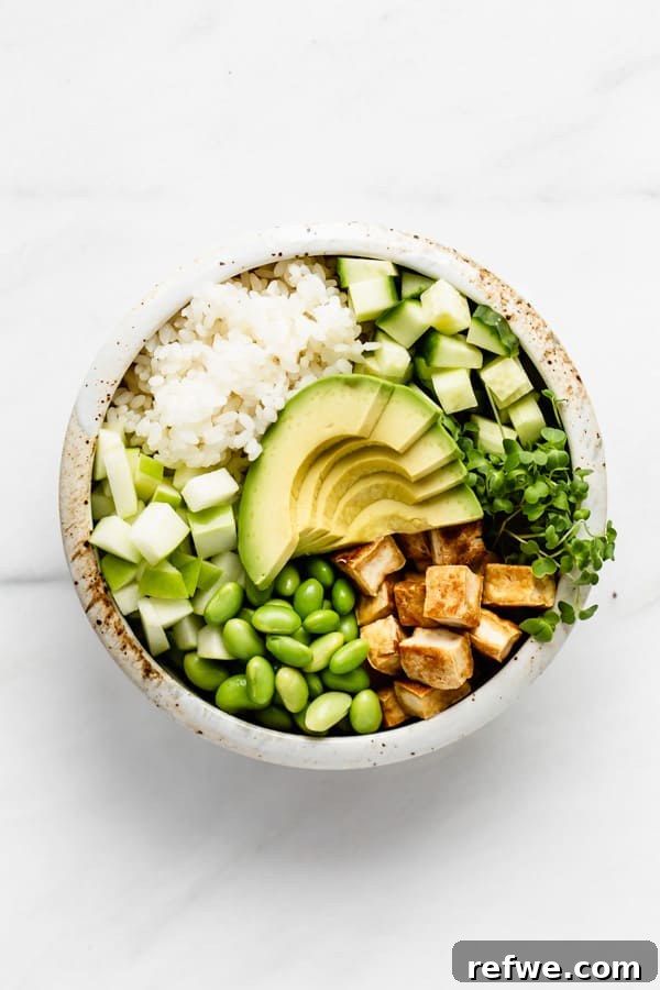 A fully assembled vegan poke bowl showcasing tofu, avocado, edamame, and various green vegetables.