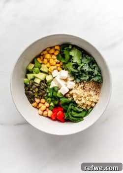 Vibrant Green Goddess Quinoa Bowl 8 a bowl of quinoa salad with vegetables, feta cheese and seeds in it