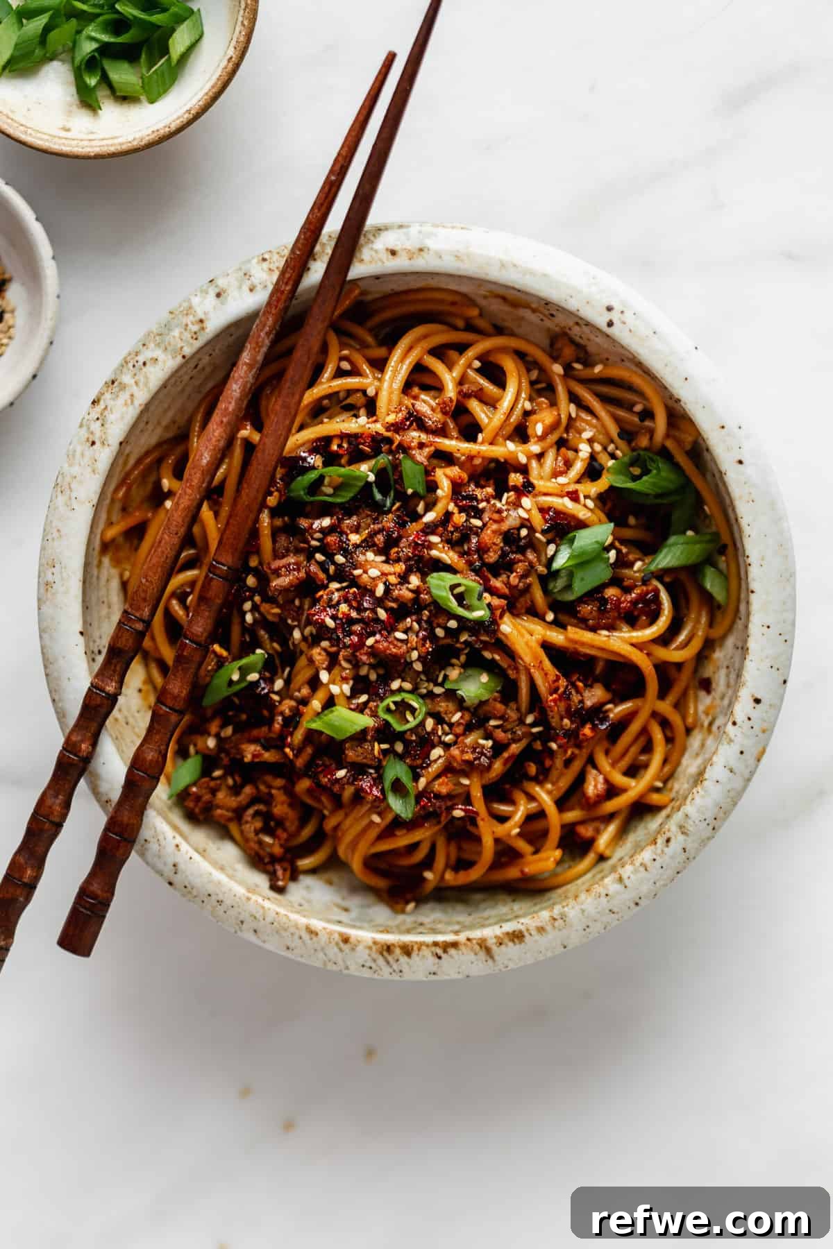 Plant-Based Dan Dan Delight 2 Vegan Dan Dan noodles topped with fresh green onions and sesame seeds, ready to be enjoyed.