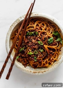 A bowl of vegan dan dan noodles with chopsticks on top