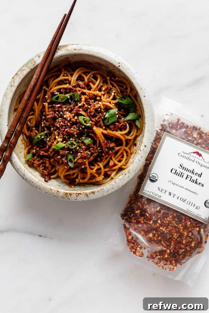 Plant-Based Dan Dan Delight 3 A bowl of vegan dan dan noodles with smoked chili flakes on the side, highlighting the key spice.
