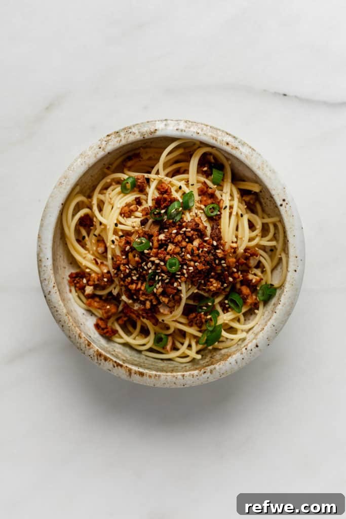 Plant-Based Dan Dan Delight 7 A bowl of noodles topped with savory vegan ground meat and fresh green onions.