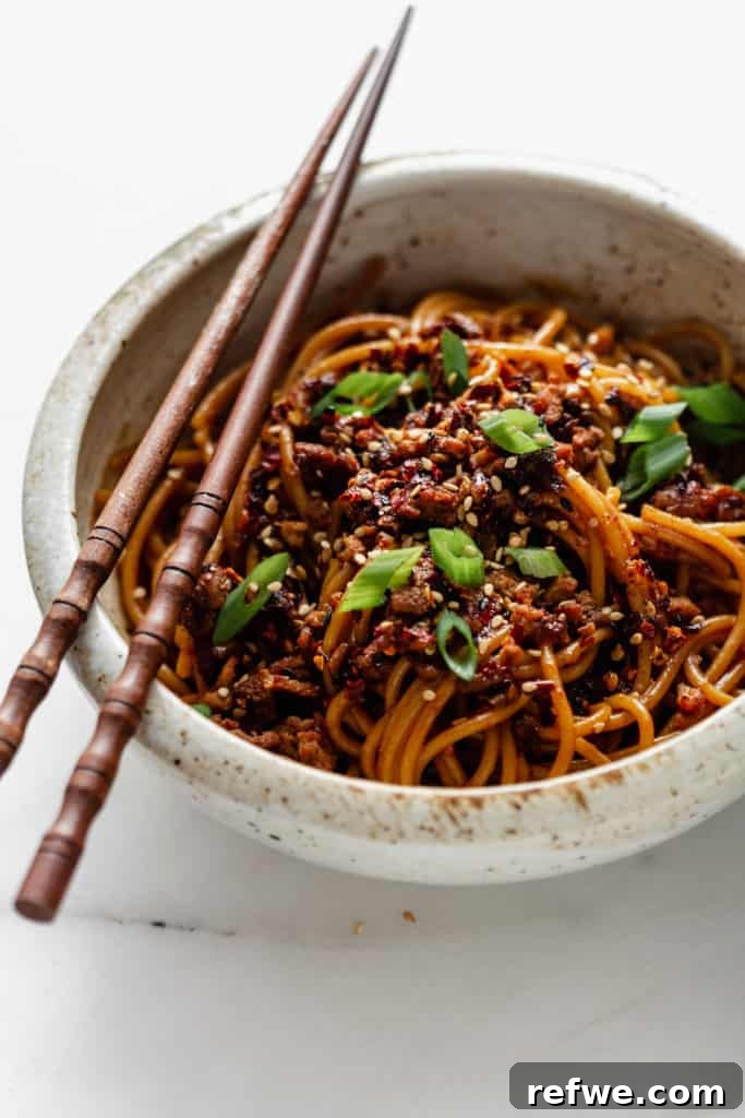 Plant-Based Dan Dan Delight 9 A bowl of vegan dan dan noodles, artfully topped with fresh green onions.