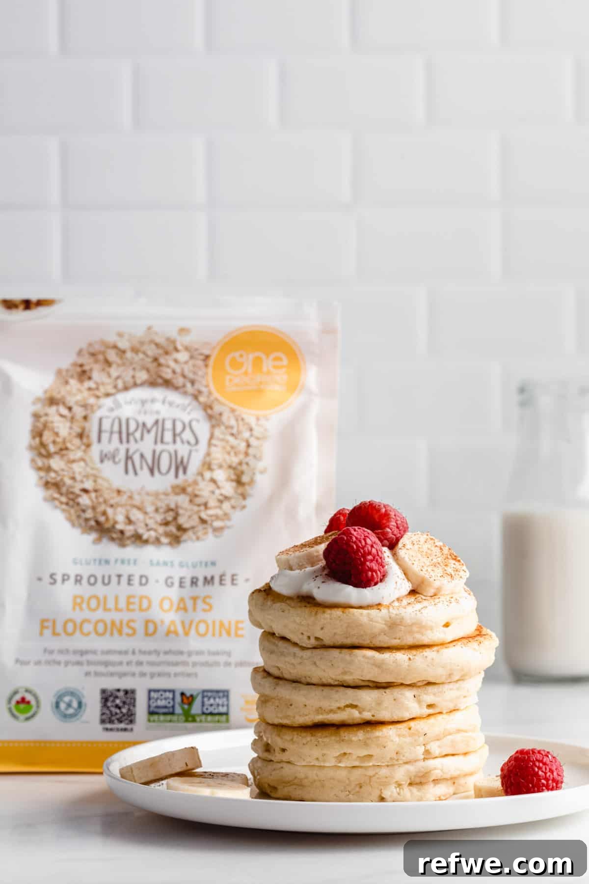 A stack of golden vegan oatmeal pancakes beside a bag of One Degree Organics Sprouted Rolled Oats, emphasizing the key ingredient.