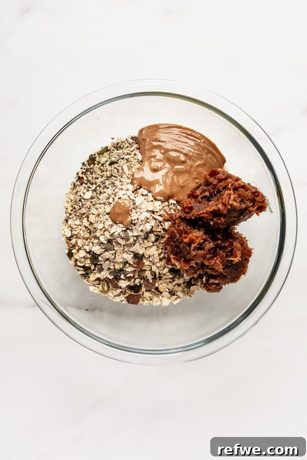 Supercharged Granola Fuel 5 A clear mixing bowl with oats, nuts, date paste and almond butter in it