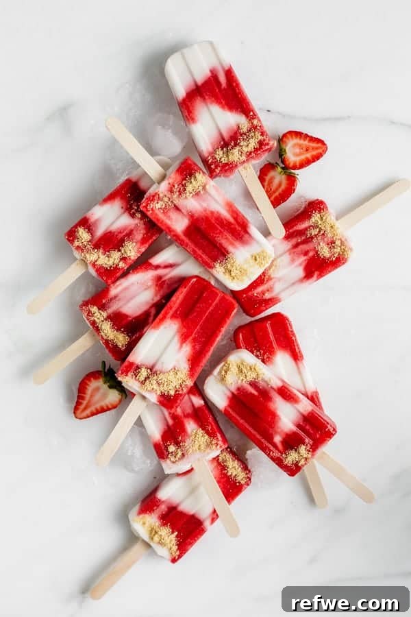 Refreshing vegan strawberry cheesecake popsicles on a marble board, perfect for summer.
