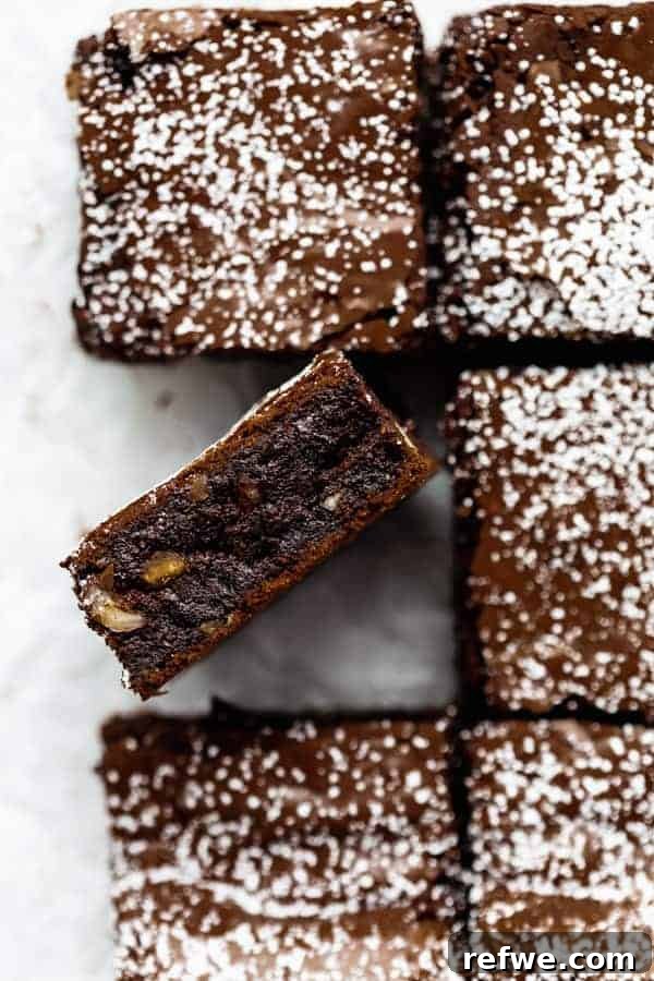 A perfectly squared flourless fudge hazelnut brownie, dusted with powdered sugar, inviting a bite.