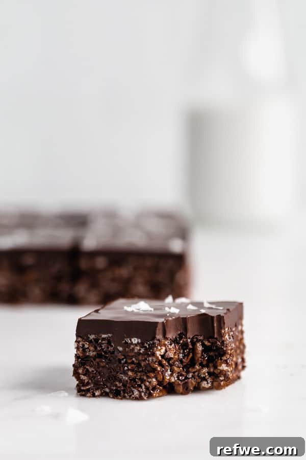 A healthy chocolate Rice Krispie treat with a corner bitten off, revealing its crispy texture and chocolate topping.