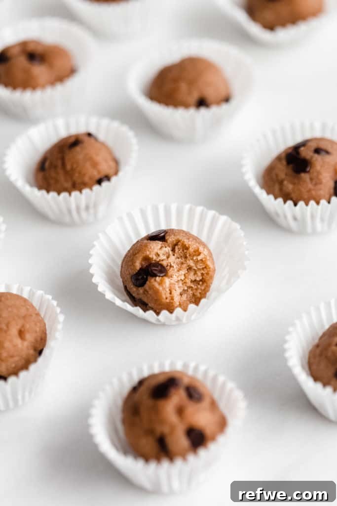 Chocolate chip cookie dough protein ball with a bite taken out, showcasing the chewy texture and chocolate chips.