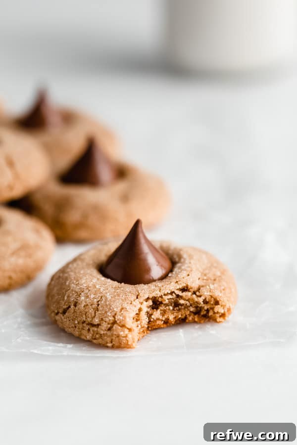 A gluten-free peanut butter blossom cookie with a chocolate kiss in the center, and a bite taken out.