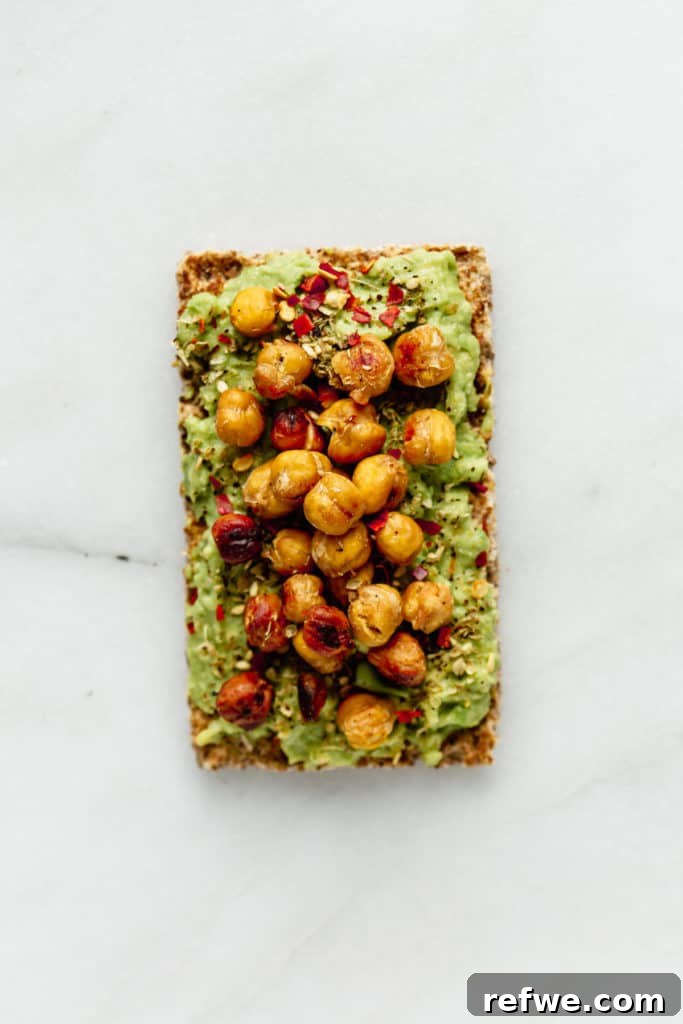 Avocado Toast: Three Creative Twists 5 A single Ryvita crispbread generously topped with creamy avocado and sprinkled with crunchy roasted chickpeas, offering a satisfying texture and protein.