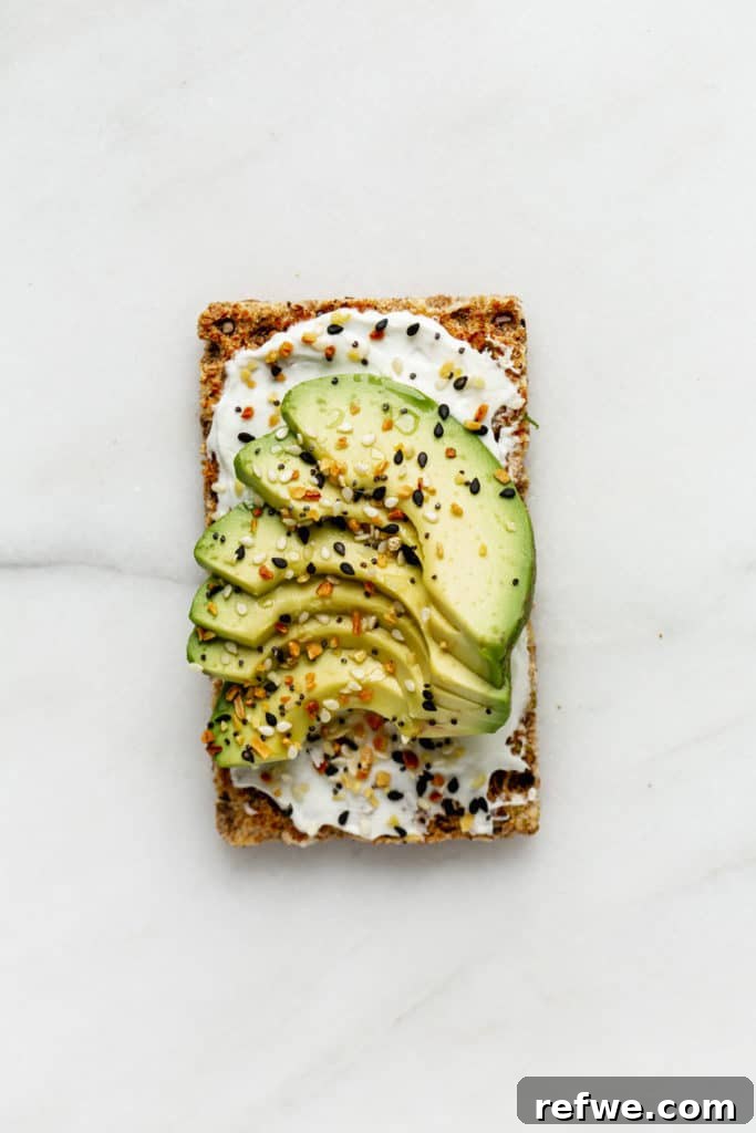 Avocado Toast: Three Creative Twists 7 A wholesome Ryvita crispbread spread with a creamy layer of cream cheese and topped with a slice of fresh avocado, creating a harmonious blend of textures and tastes.