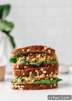 two chickpea salad sandwiches stacked on a marble counter