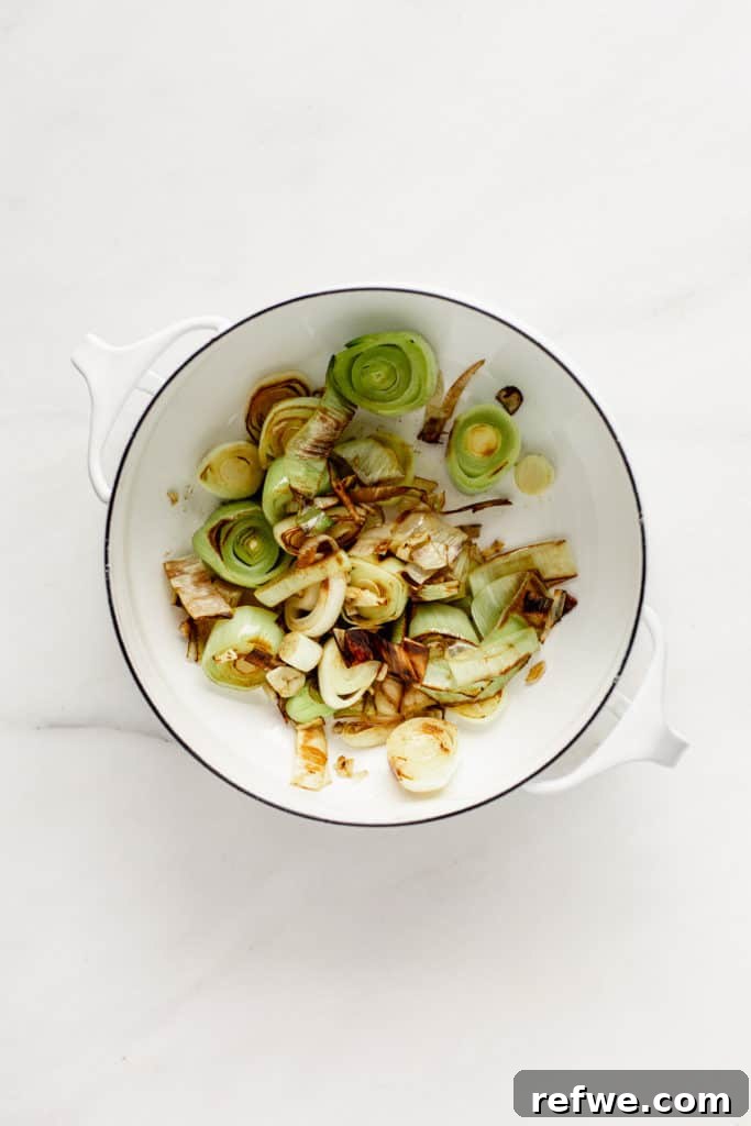 Sautéed leeks in a white pot, preparing the aromatic base for the soup.