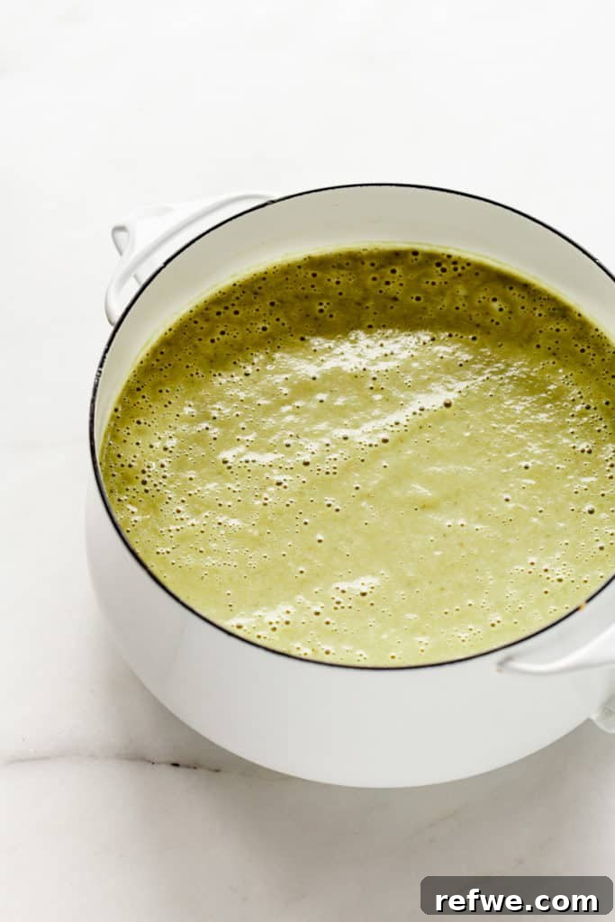 A white pot filled with creamy, perfectly blended vegan asparagus soup.