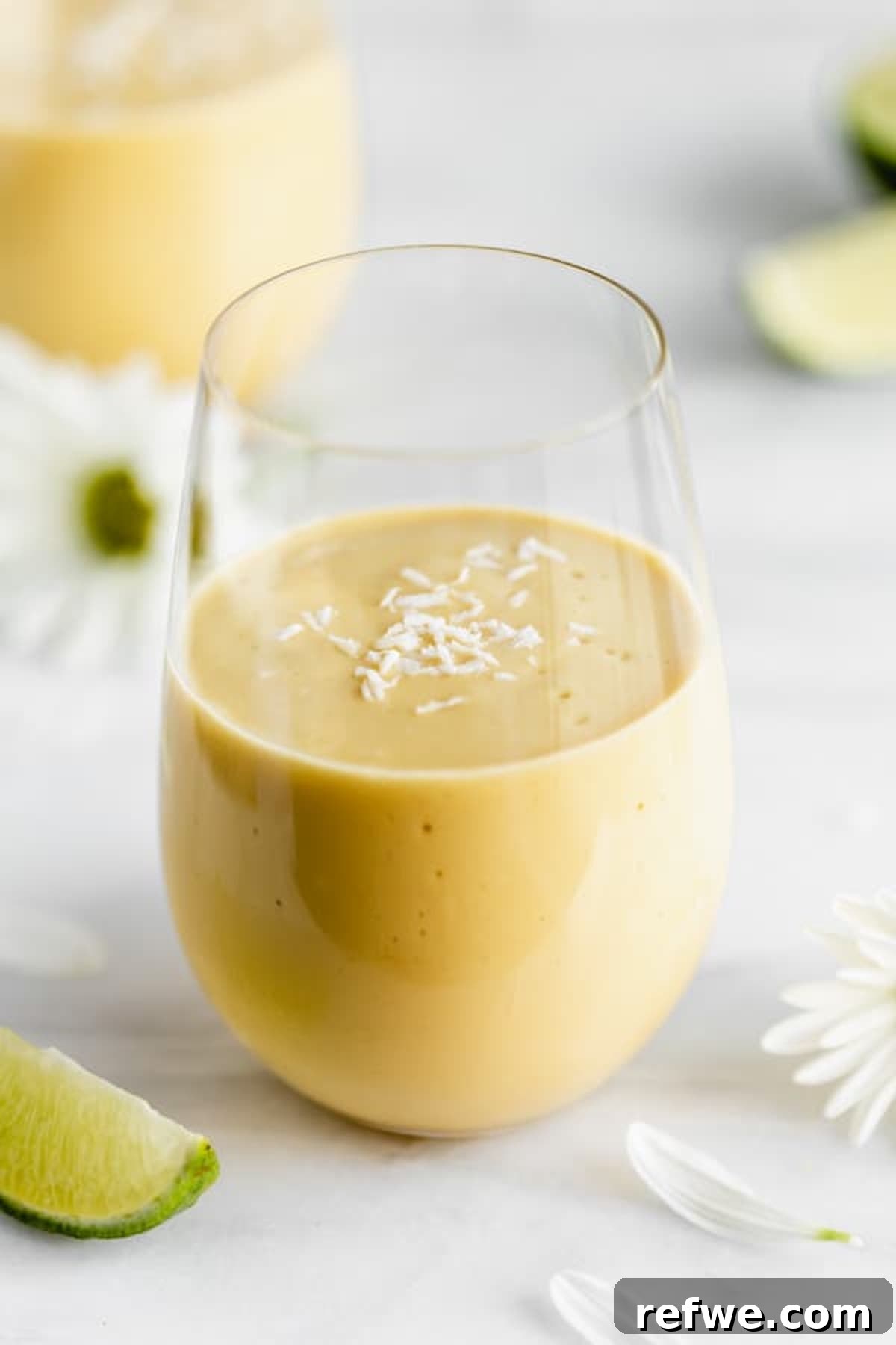 23 Simple Wholesome Morning Smoothies 13 A vegan mango lassi smoothie in a class topped with shredded coconut