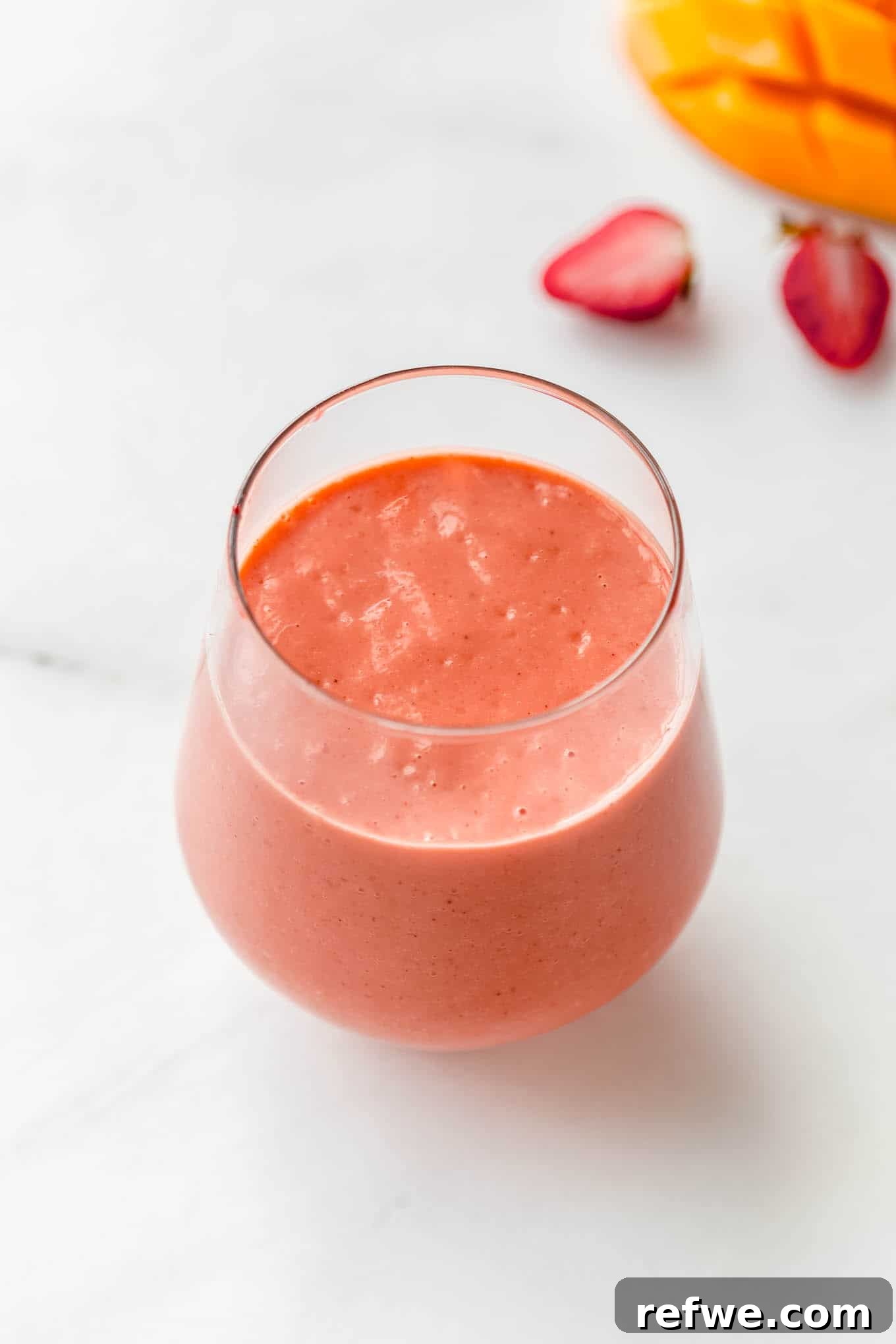 23 Simple Wholesome Morning Smoothies 14 a glass of strawberry mango smoothie on a marble counter