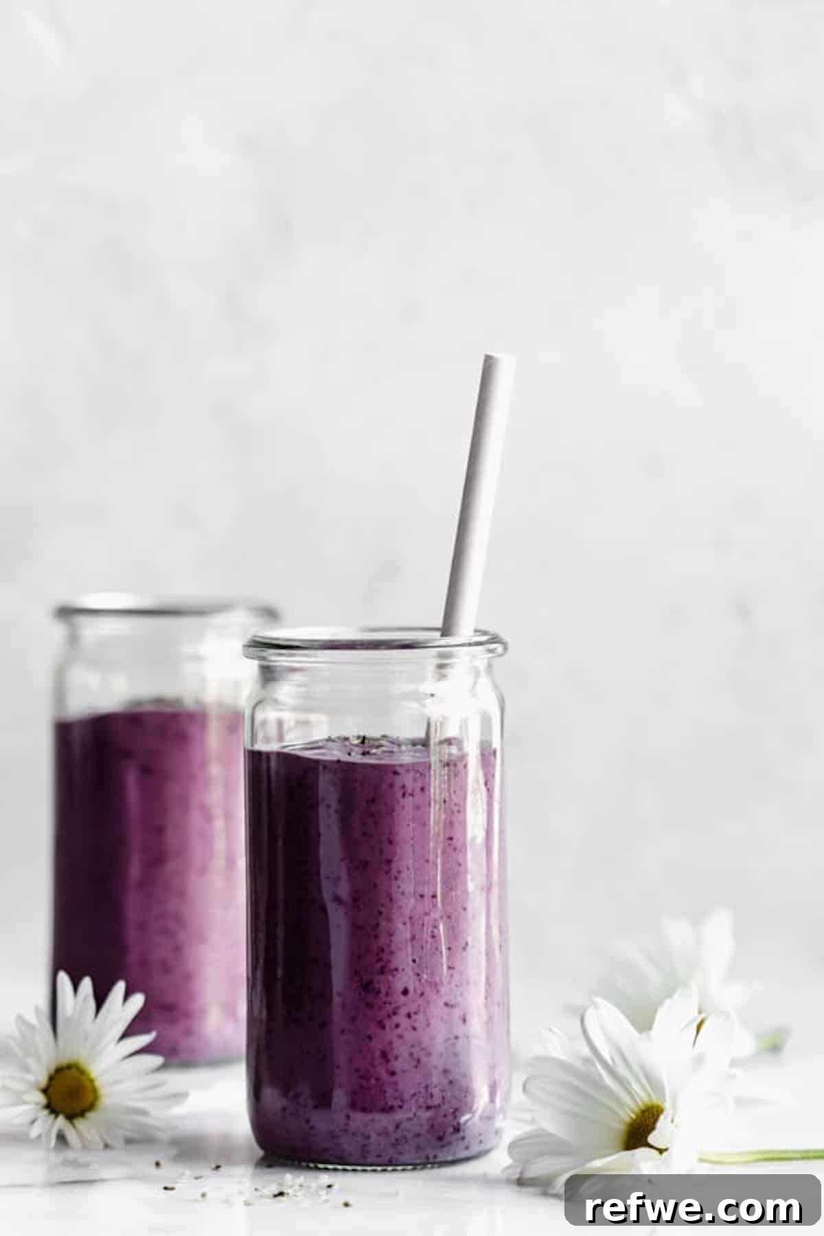 23 Simple Wholesome Morning Smoothies 17 Two jars with purple smoothies in them with white flowers around them