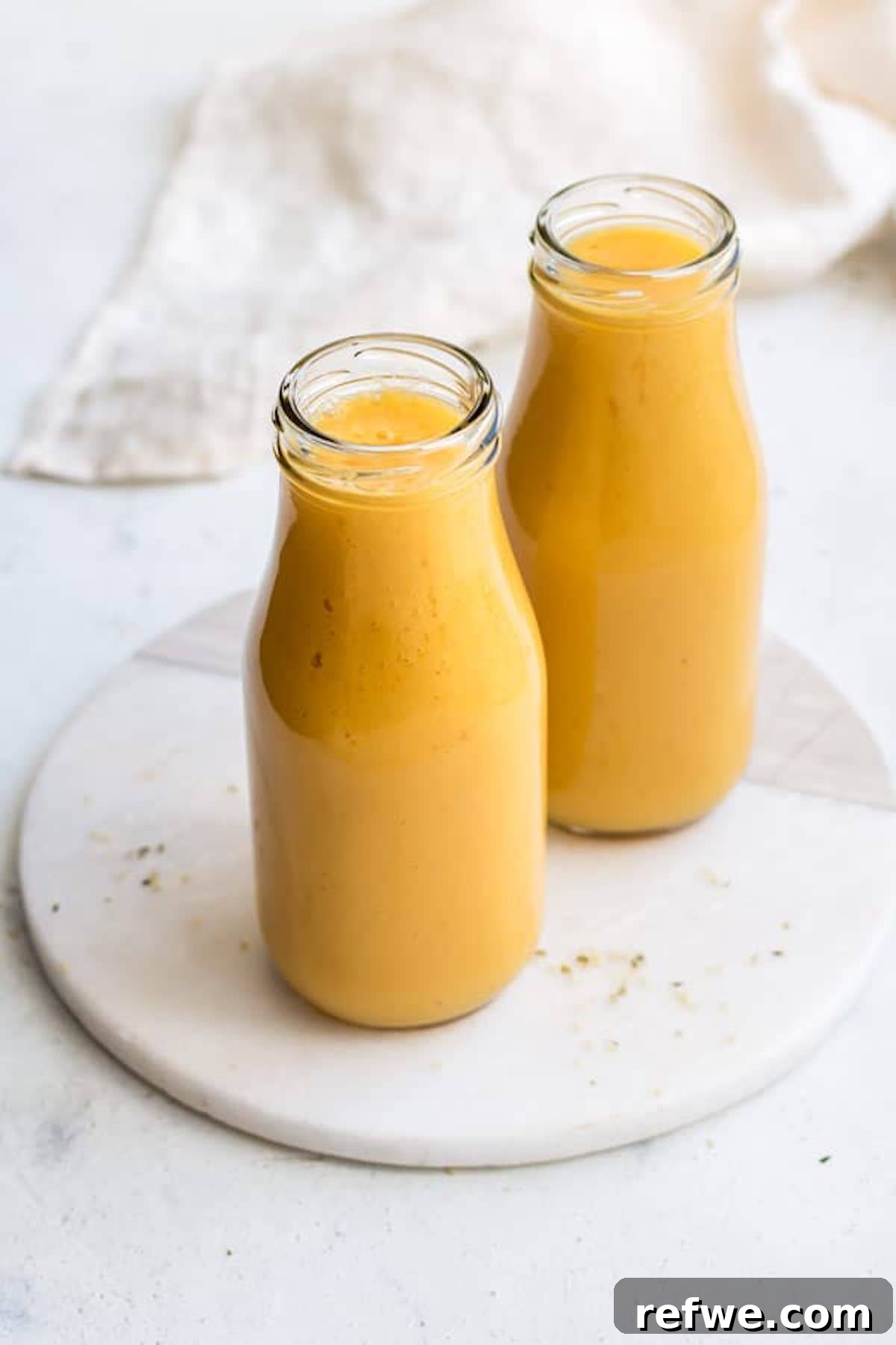23 Simple Wholesome Morning Smoothies 22 two tall glasses of a bright yellow mango smoothie made from healthy smoothie recipes to make your insides glow