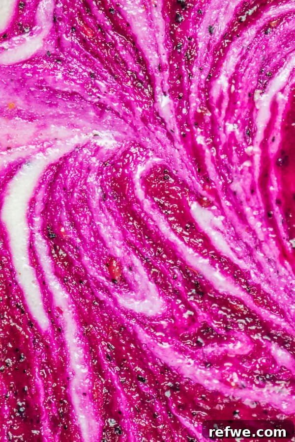 Frozen Vegan Dragon Fruit Cheesecake Bars Close-up of a single raw vegan dragon fruit cheesecake bar, showing the creamy texture, vivid pink swirl, and dense brownie-like crust.