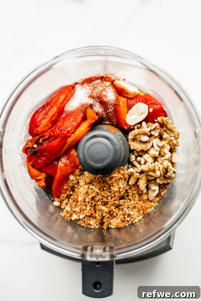 Roasted Red Pepper Walnut Muhammara 4 A food processor bowl with roasted red peppers, breadcrumbs, walnuts, and garlic ready to be blended into Muhammara.