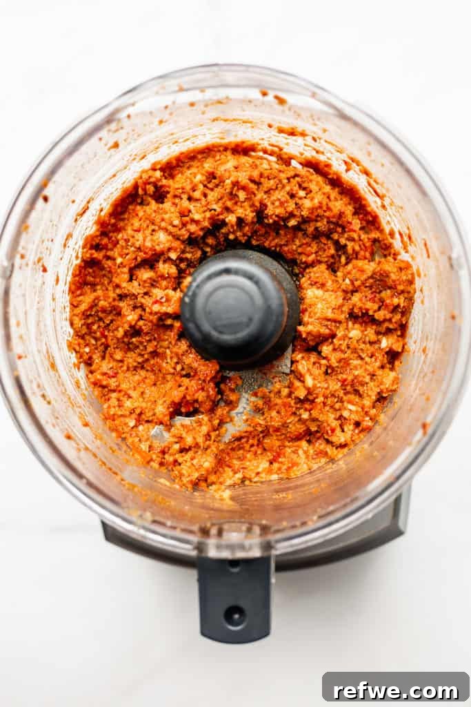 Roasted Red Pepper Walnut Muhammara 5 A food processor actively blending the ingredients into a smooth, vibrant roasted red pepper dip.