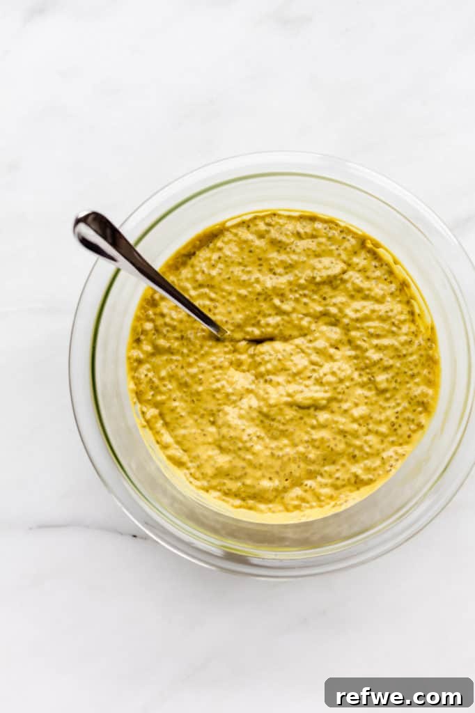 A clear mixing bowl filled with the mango chia pudding mixture, smooth and vibrant, indicating it has been thoroughly combined.