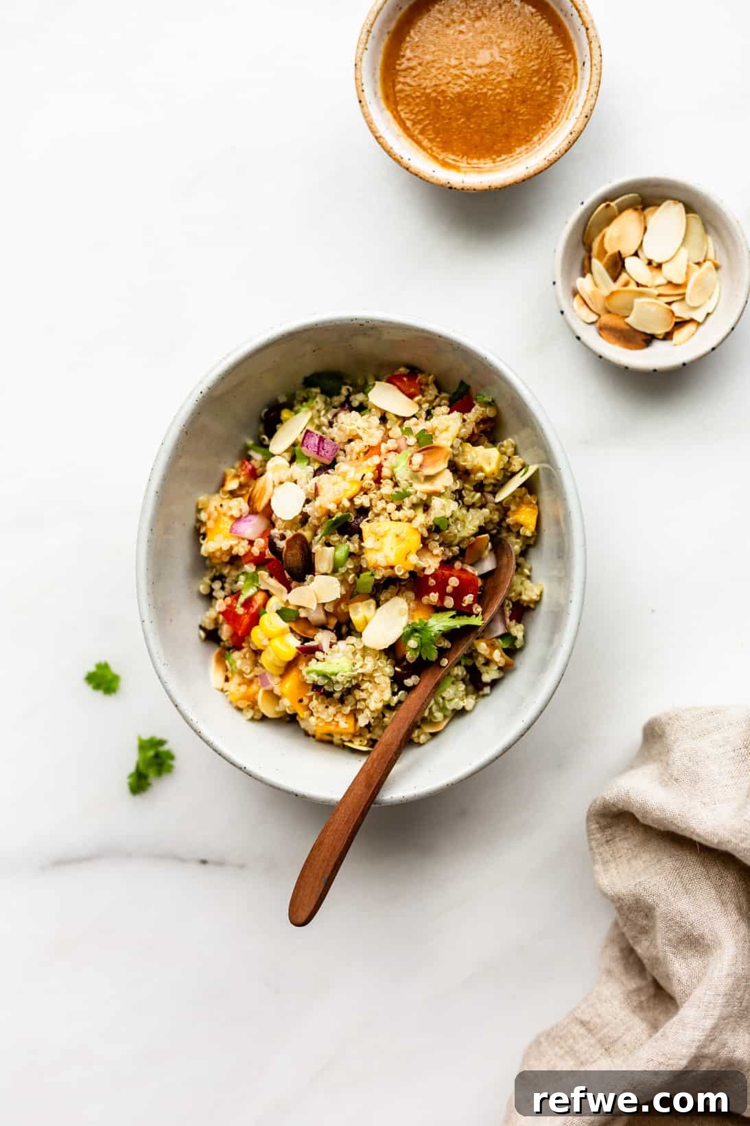 Zesty Southwestern Quinoa Power Bowl 5 A beautifully plated bowl of Southwest Quinoa Salad, garnished with a sprinkle of toasted almonds, accompanied by two small side bowls of chili lime dressing for individual customization.