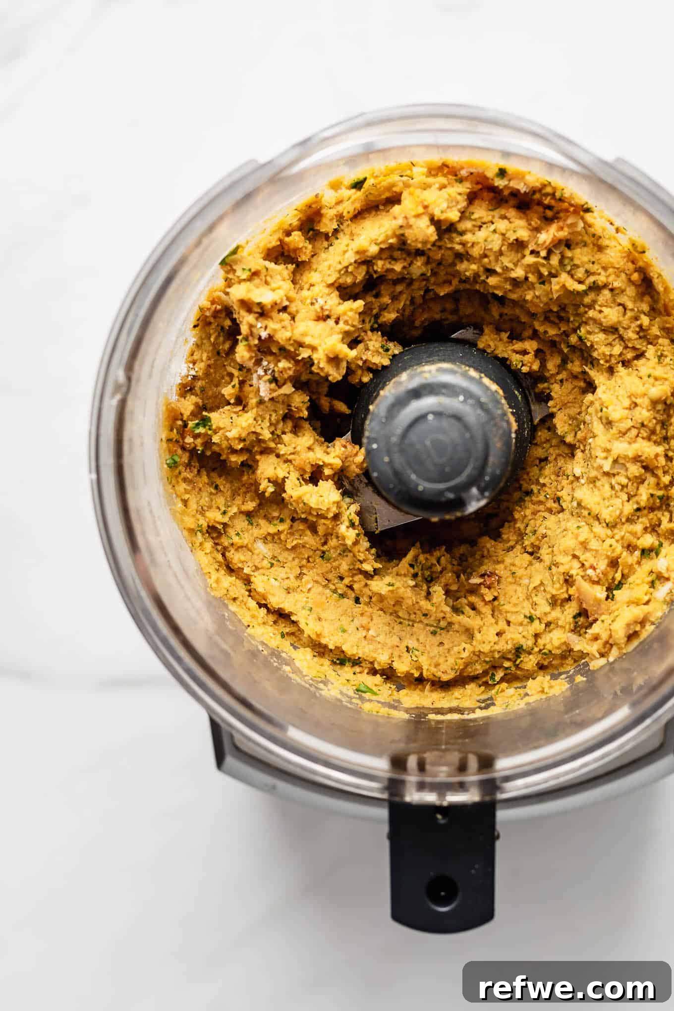 Sweet Potato and Chili Falafel 4 A smooth, greenish-orange sweet potato falafel mixture in a food processor bowl after blending.