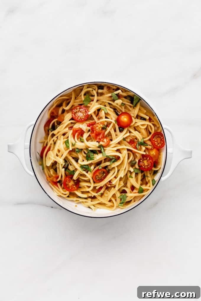 Effortless One-Pan Tomato Basil Pasta 4 A white pot filled with perfectly cooked linguine pasta, vibrant cherry tomatoes, capers, and fresh basil, simmering in its sauce.