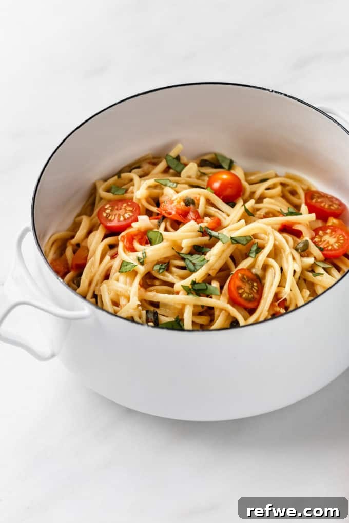 Effortless One-Pan Tomato Basil Pasta 5 Perfectly cooked linguine with fresh basil and cherry tomatoes, beautifully arranged in a white pot, ready for serving.